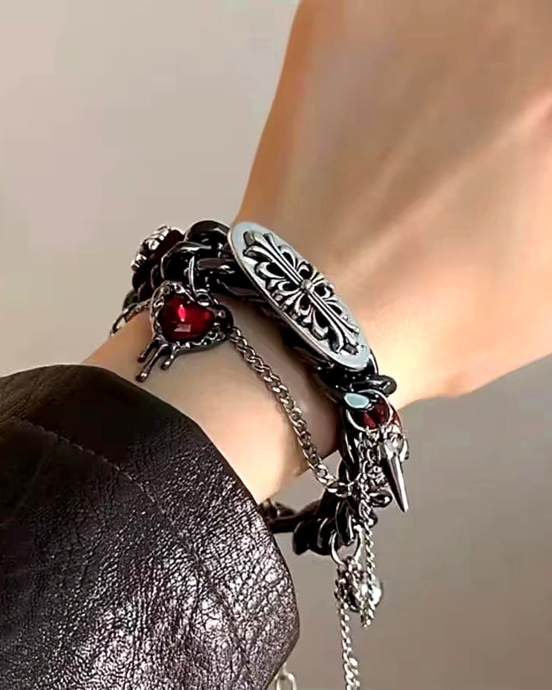Chain bracelet with an engraved silver plate and red heart charms, worn on the wrist